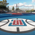 Outdoor basketball court with a colorful logo at center court.