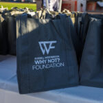 Black bags with Why Nott Foundation logo on a table.