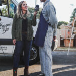 Two people chatting at an outdoor market, one holding coffee.