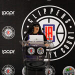 A woman speaks at a podium during a Clippers basketball event.