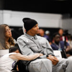 Young man in gray outfit and beanie sitting attentively at an event.