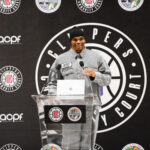 Man speaking at a podium during a basketball event.