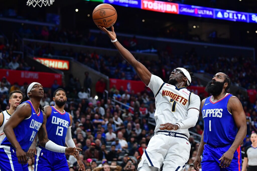 Basketball player making an acrobatic layup during a game.