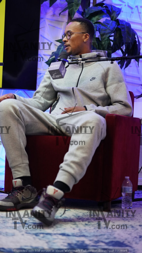 Person wearing matching grey sweatpants and hoodie sitting on a red chair.