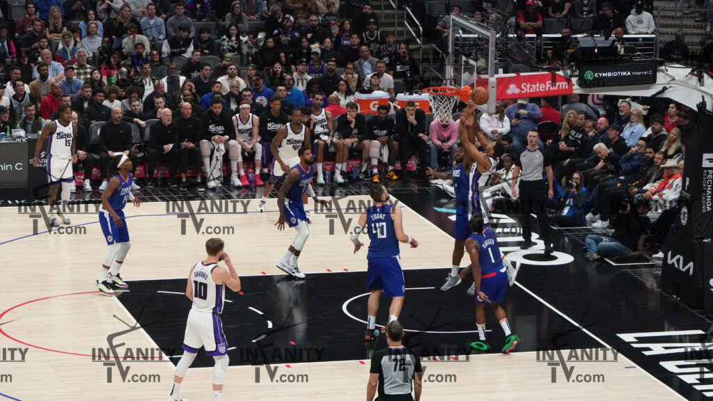 Basketball player dunking during a game with spectators watching.