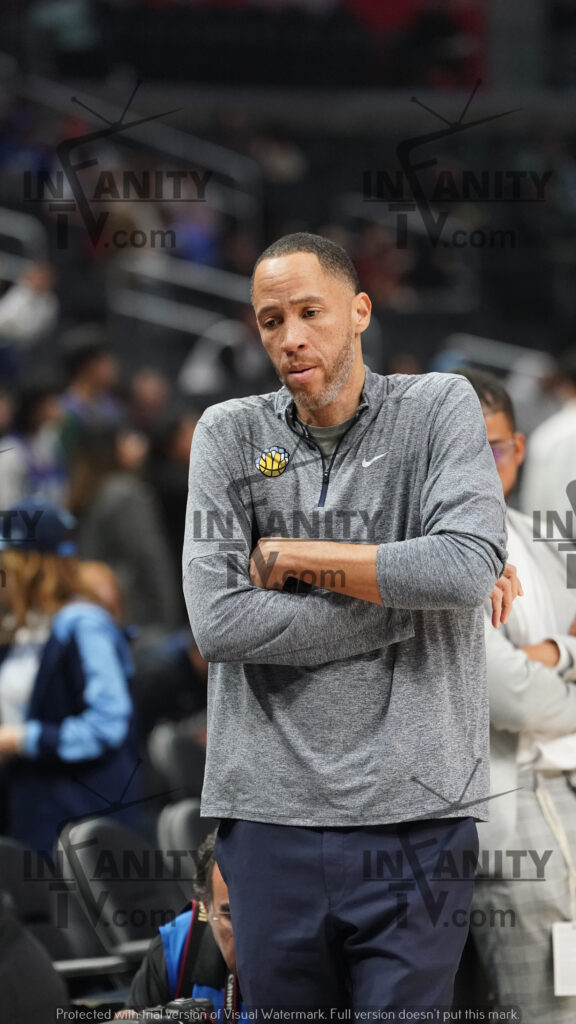 A basketball player warming up on the court with arms crossed.
