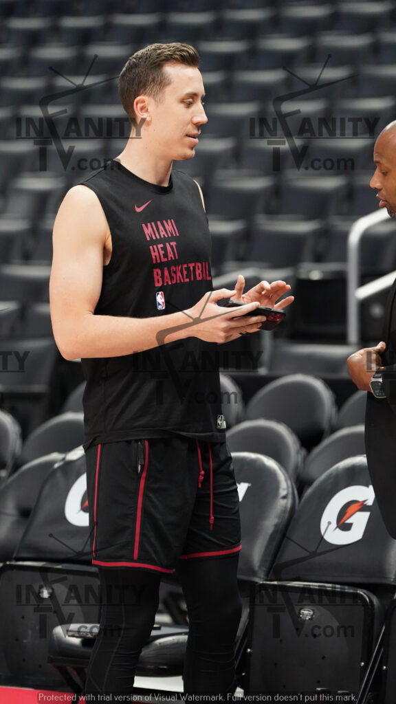 Basketball player checking phone during practice session.