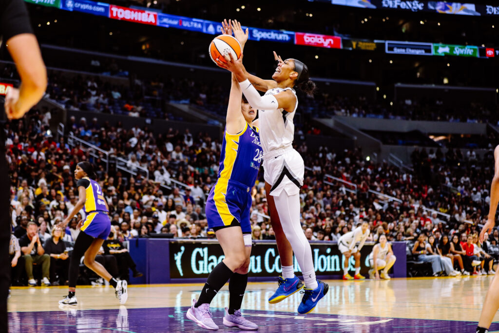 A basketball player leaps to shoot over a defender during a game.