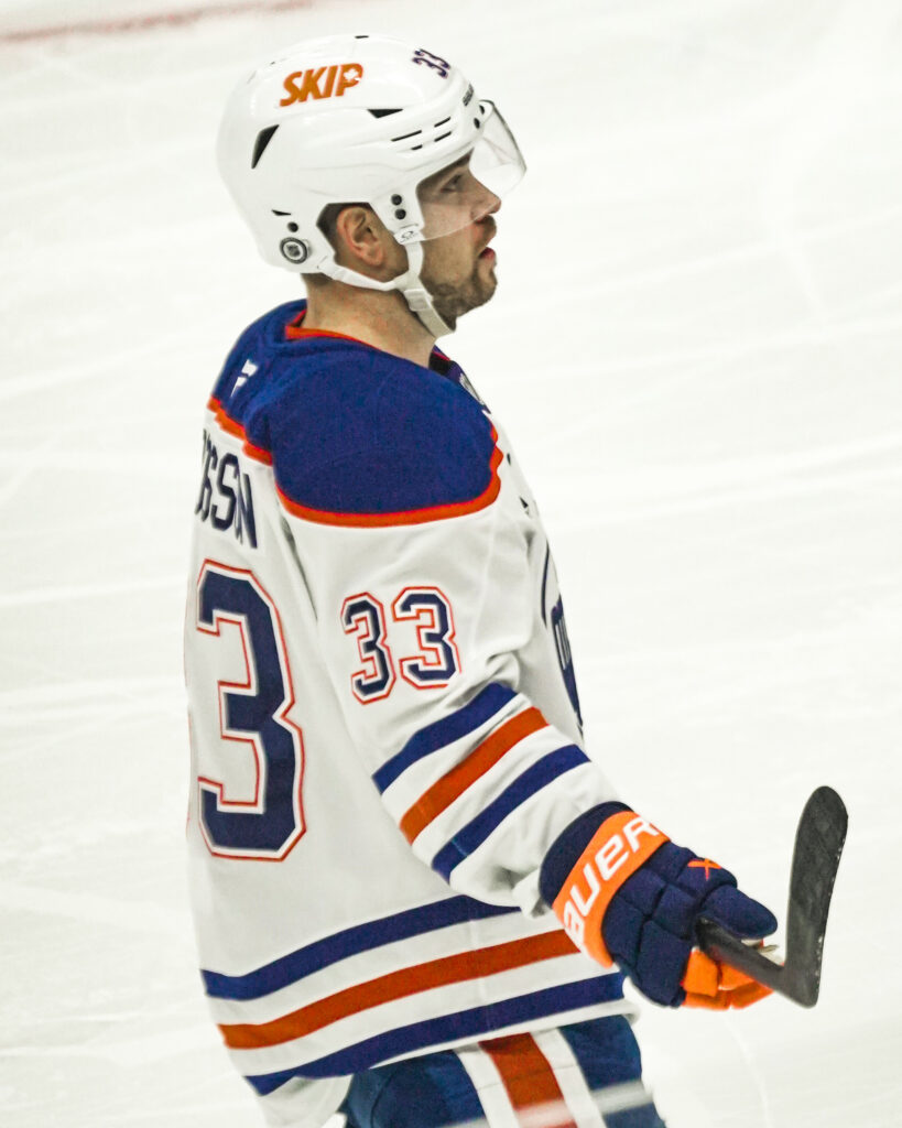 Hockey player in white and blue jersey with number 33 on ice.