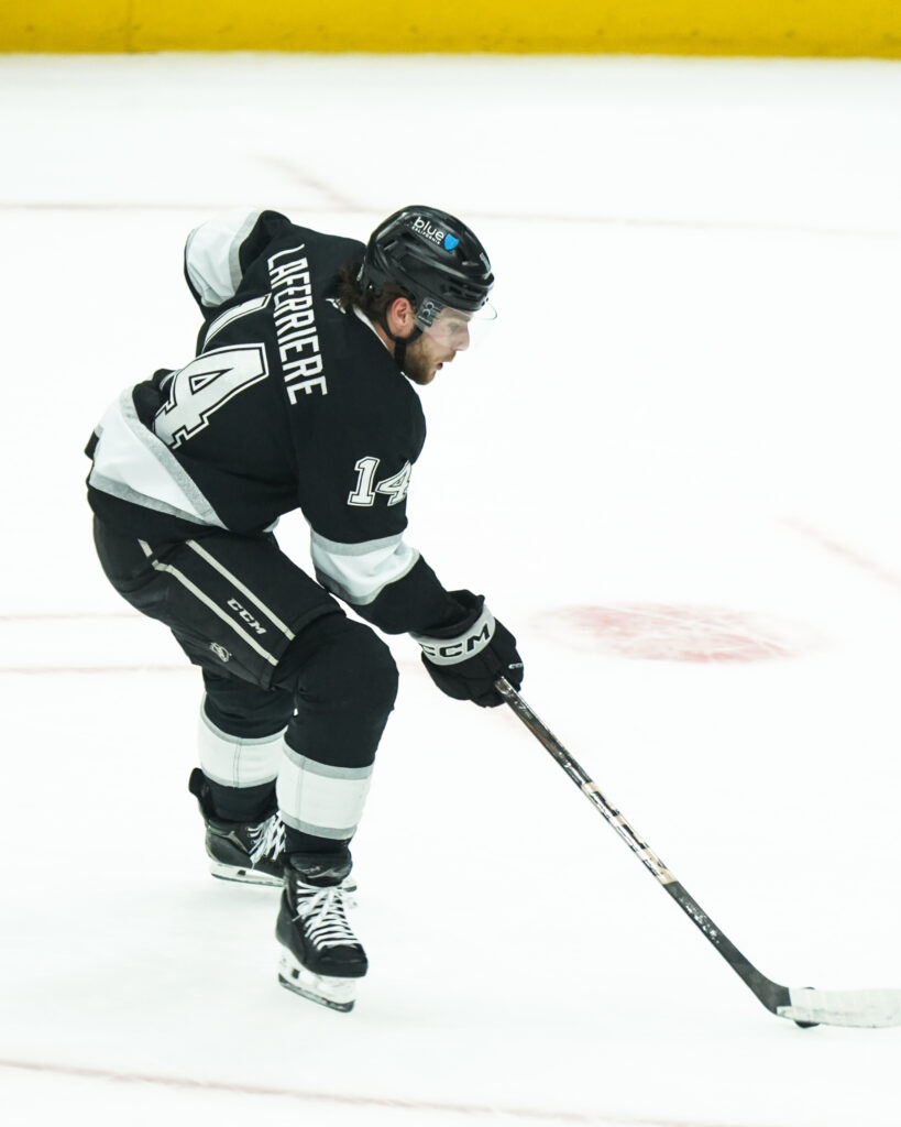 Ice hockey player in black uniform controlling the puck during a game.