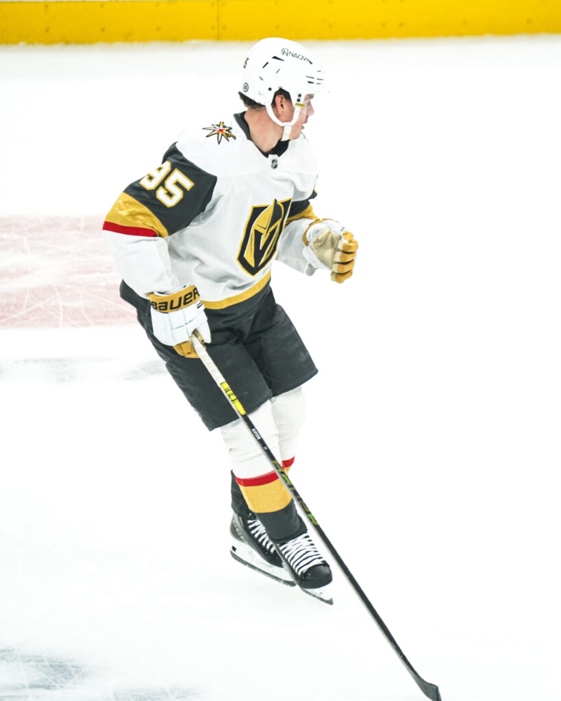 Hockey player in white and black Vegas Golden Knights uniform on ice.