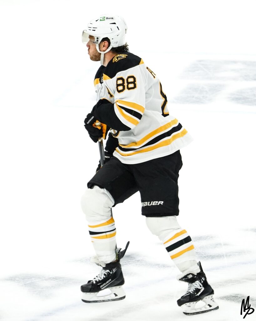Ice hockey player in Boston Bruins uniform skating on ice.