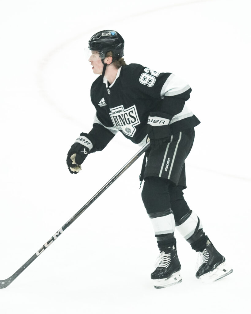 Ice hockey player in black uniform skating on ice.