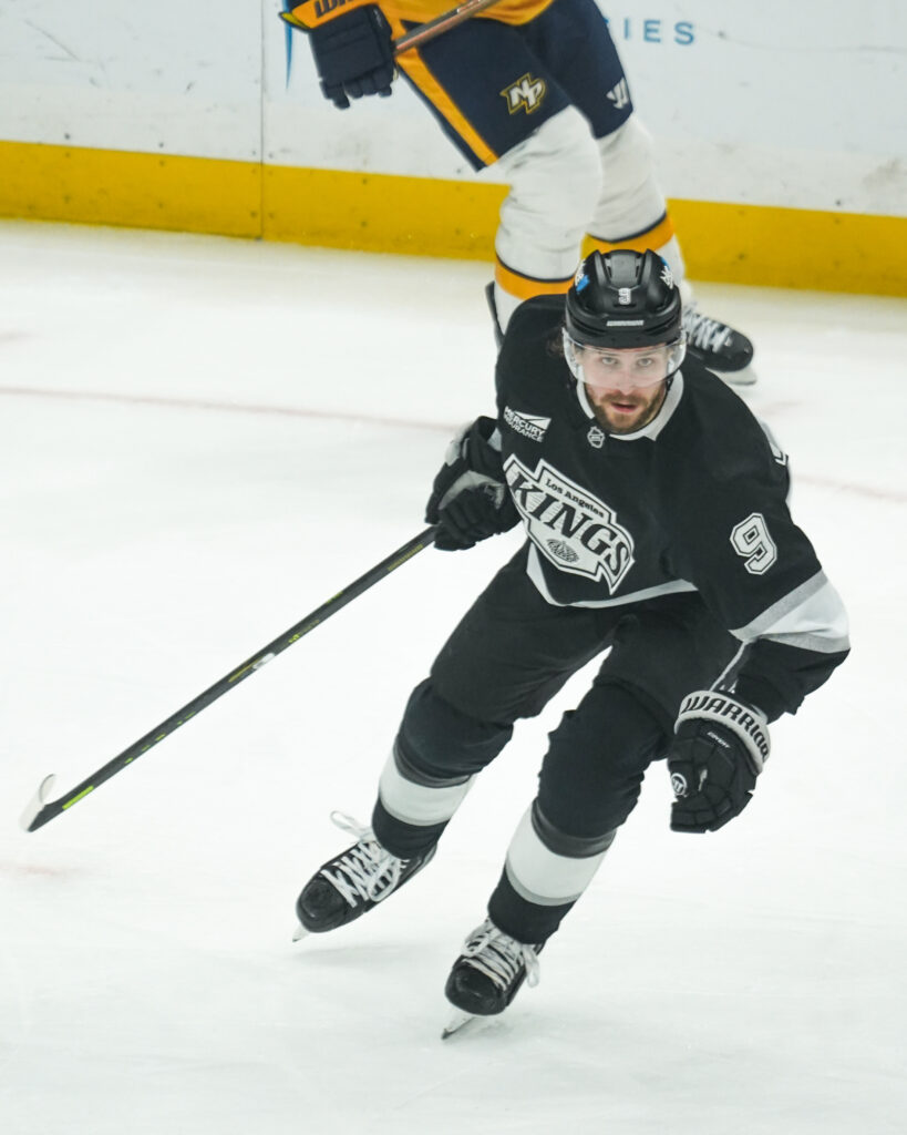 Ice hockey player in black uniform skating on ice during a game.