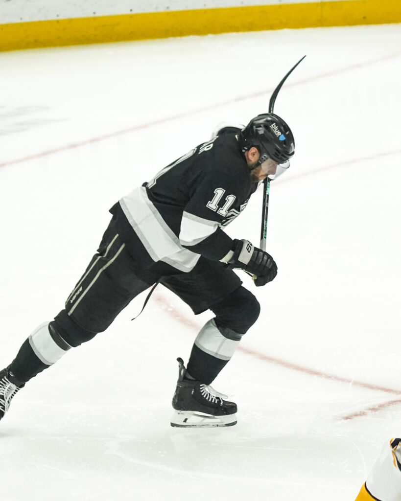 Ice hockey player in black jersey skating intensely on the rink.