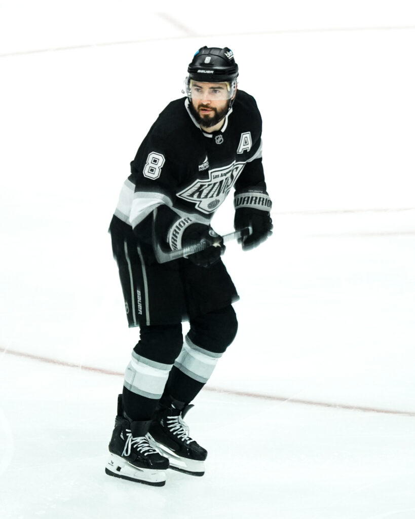 A hockey player in black and white uniform skating on ice.