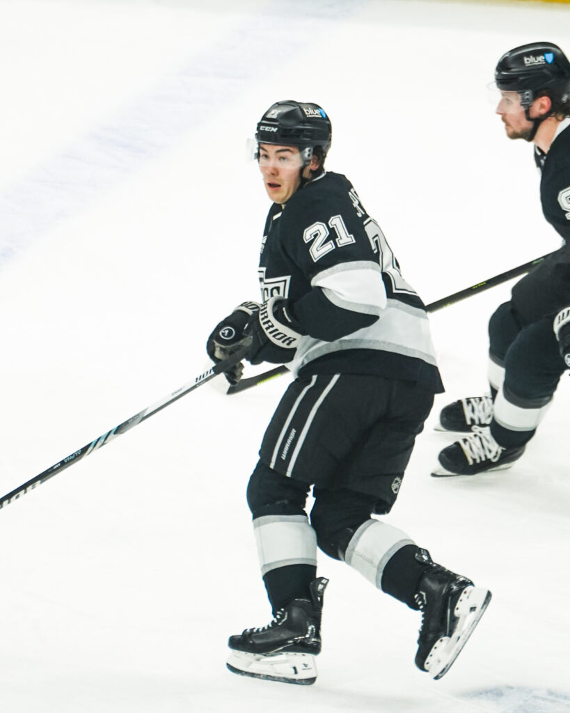 Ice hockey player in black and white uniform skating on ice.