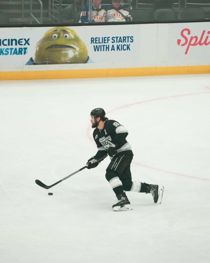 Ice hockey player skating with puck on the rink.