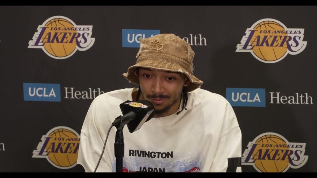 Man wearing a bucket hat speaking into a microphone.