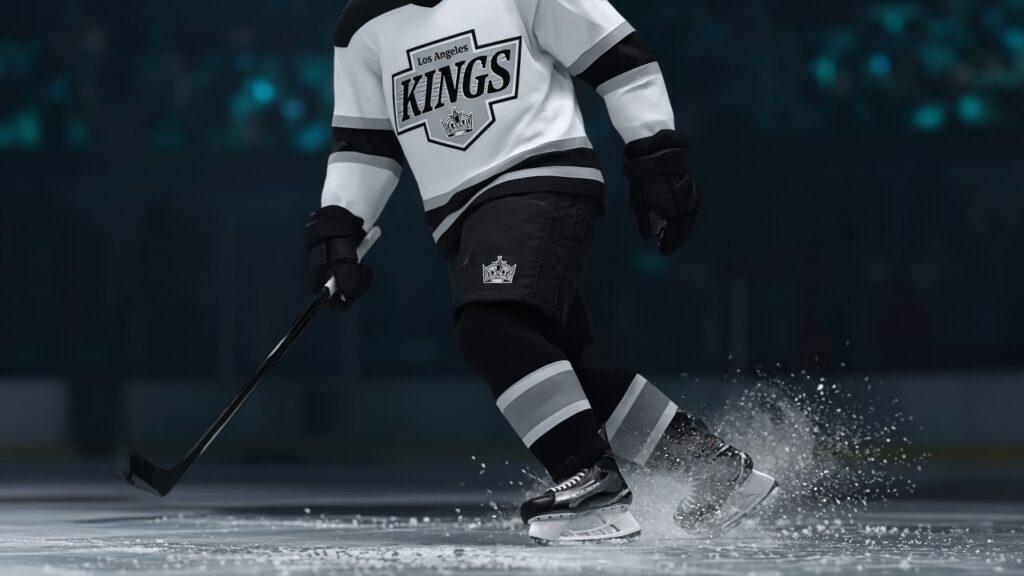 A Kings forward in the white road jersey with the Los Angeles Kings crest skates across the ice, spraying snow, in a dimly lit arena after the overtime loss in San Jose